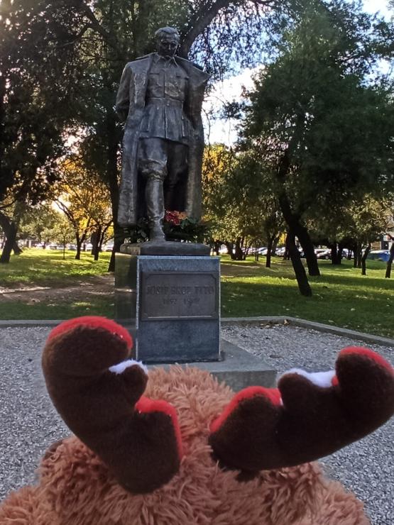 Travelmoose looking waaaay up at a statue of a solemn faced man, who is staring down at him. The man is wearing a military uniform, including tall cavalry boots and a long greatcoat. The inscription at the base of the statue reads "JOSIP BROZ TITO, 1892—1980".