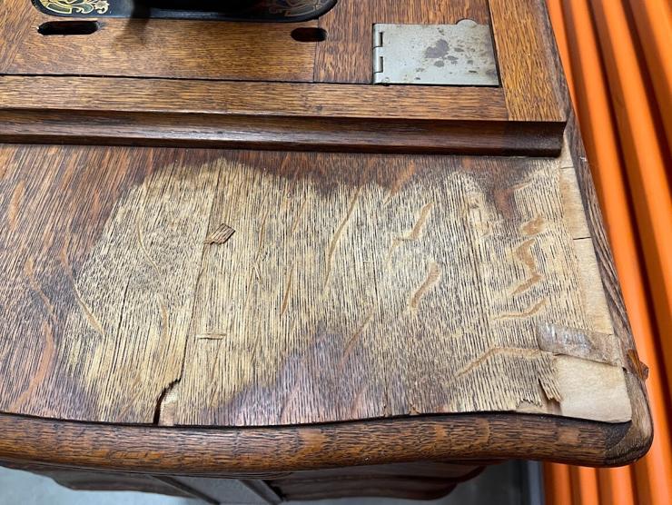 Close up view of water damage and veneer peeling from cabinet surface. 